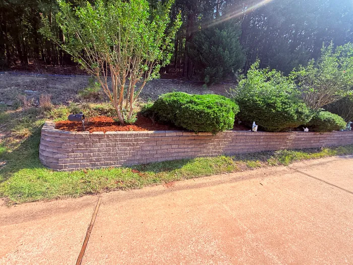 Stacked-stone garden bed with fresh mulch along the driveway